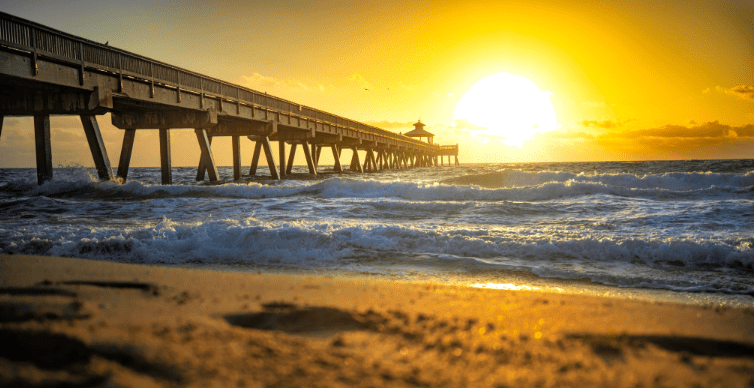 Sunset beach pier with waves.